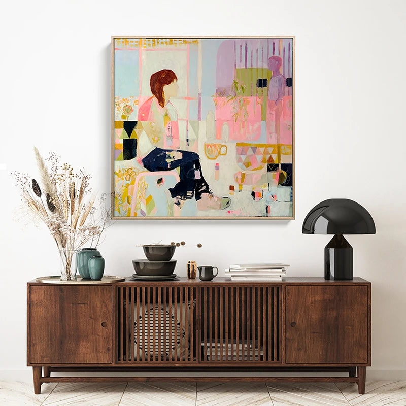 Abstract figure framed art reproduction print hanging on a wall and styled above a dark wood sideboard.