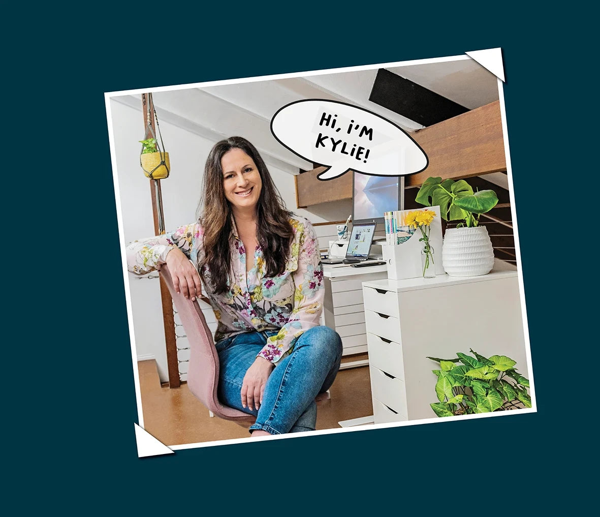 Ugli Art founder sitting in her art studio smiling with text saying 'Hi, I'm Kylie'